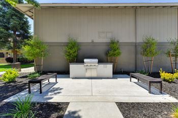 Exterior BBQ grill and courtyard with bench seating. area